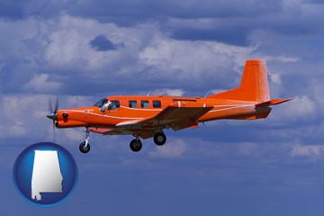 a red turboprop aircraft flying in a blue sky with cumulus clouds - with Alabama icon