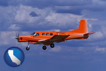 a red turboprop aircraft flying in a blue sky with cumulus clouds - with California icon