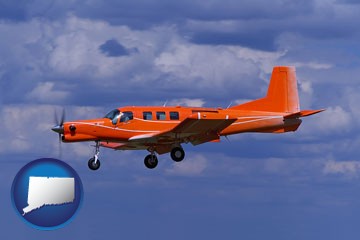 a red turboprop aircraft flying in a blue sky with cumulus clouds - with Connecticut icon