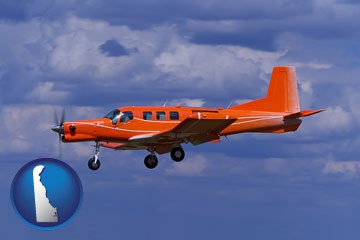a red turboprop aircraft flying in a blue sky with cumulus clouds - with Delaware icon