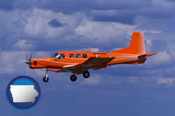 a red turboprop aircraft flying in a blue sky with cumulus clouds - with Iowa icon