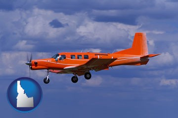 a red turboprop aircraft flying in a blue sky with cumulus clouds - with Idaho icon