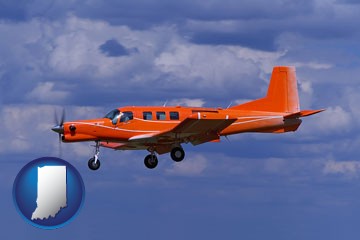 a red turboprop aircraft flying in a blue sky with cumulus clouds - with Indiana icon
