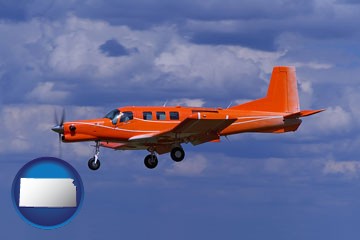 a red turboprop aircraft flying in a blue sky with cumulus clouds - with Kansas icon