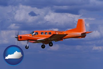 a red turboprop aircraft flying in a blue sky with cumulus clouds - with Kentucky icon