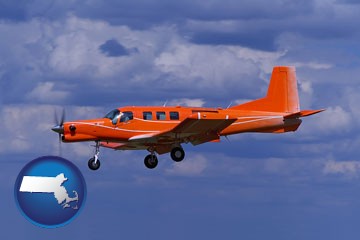 a red turboprop aircraft flying in a blue sky with cumulus clouds - with Massachusetts icon