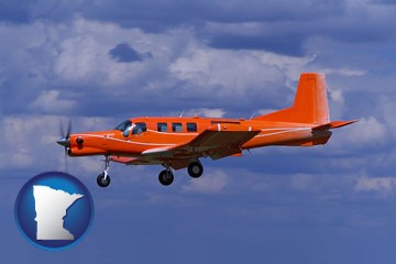 a red turboprop aircraft flying in a blue sky with cumulus clouds - with Minnesota icon