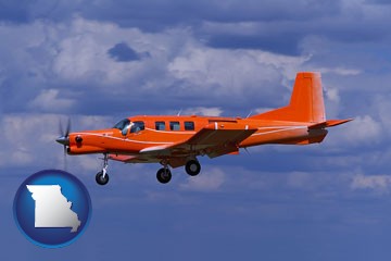 a red turboprop aircraft flying in a blue sky with cumulus clouds - with Missouri icon