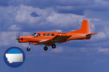 a red turboprop aircraft flying in a blue sky with cumulus clouds - with Montana icon
