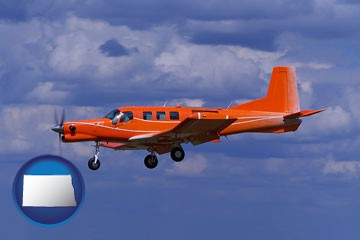 a red turboprop aircraft flying in a blue sky with cumulus clouds - with North Dakota icon