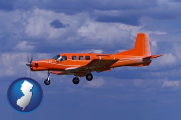 a red turboprop aircraft flying in a blue sky with cumulus clouds - with New Jersey icon