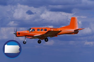a red turboprop aircraft flying in a blue sky with cumulus clouds - with Pennsylvania icon