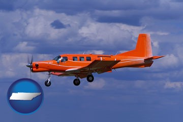 a red turboprop aircraft flying in a blue sky with cumulus clouds - with Tennessee icon