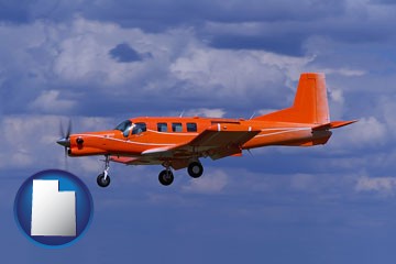 a red turboprop aircraft flying in a blue sky with cumulus clouds - with Utah icon