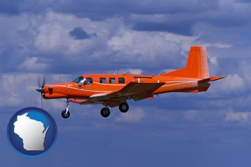 a red turboprop aircraft flying in a blue sky with cumulus clouds - with Wisconsin icon