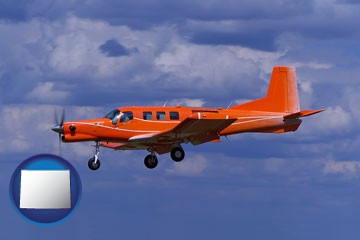 a red turboprop aircraft flying in a blue sky with cumulus clouds - with Wyoming icon