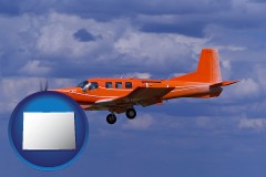 colorado map icon and a red turboprop aircraft flying in a blue sky with cumulus clouds