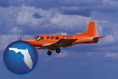 florida map icon and a red turboprop aircraft flying in a blue sky with cumulus clouds