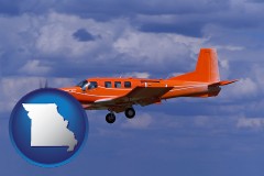 missouri map icon and a red turboprop aircraft flying in a blue sky with cumulus clouds