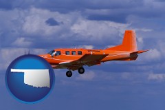 oklahoma map icon and a red turboprop aircraft flying in a blue sky with cumulus clouds